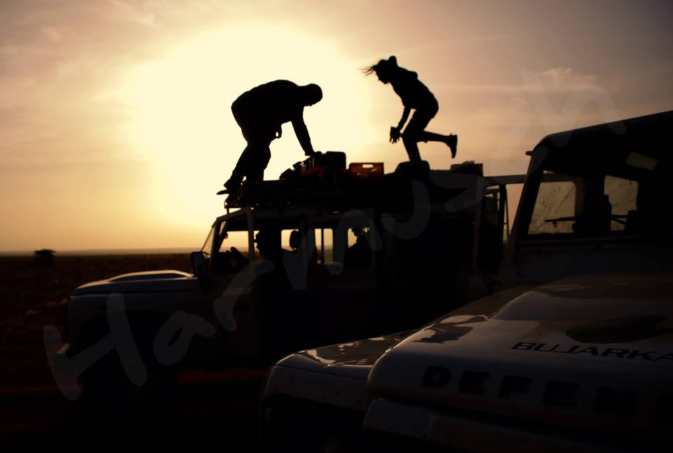 Investigadores de Harmusch preparando equipo sobre los Land Rover al atardecer en el Sáhara